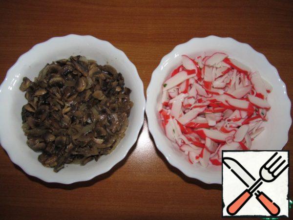 Mushrooms cut into thin slices, onion - half rings, fry with the addition of oil, salt and pepper. Then cool the mushrooms, drain the excess oil. Cut crab sticks into slices diagonally.
