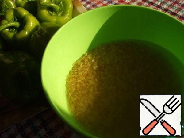 Pour Bulgur with a glass of boiling water, cover, set aside for 15 minutes. Let it swell.
Cut off the top of the peppers, remove the partitions with seeds.