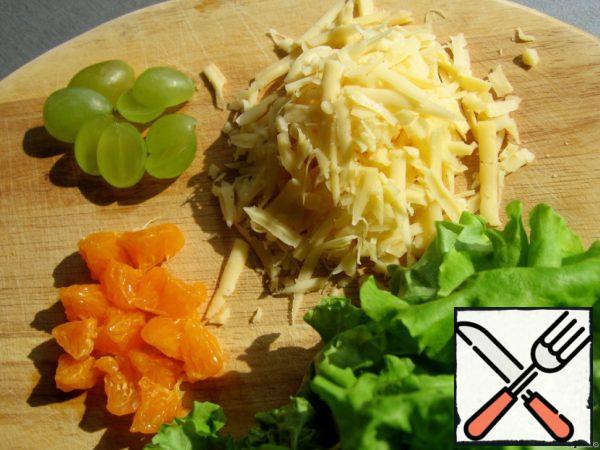Cut the grapes in half. Peel the tangerine and white films, cut each slice into three parts. Grate the cheese on a coarse grater.
Pre-divide the yogurt into 2 parts: mix one with cheese, the other with an apple cut into long strips.