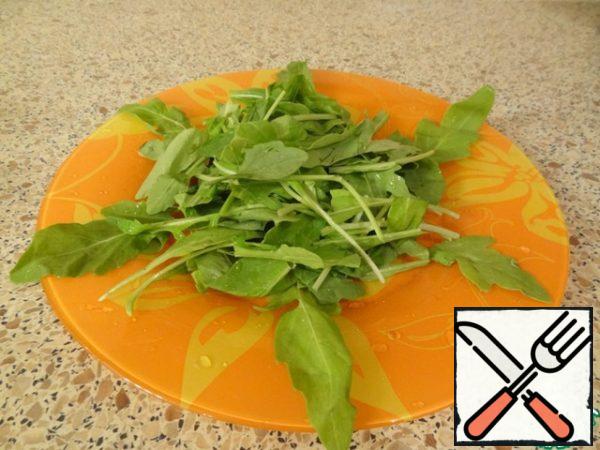 Place the arugula on a flat salad plate in the middle.
