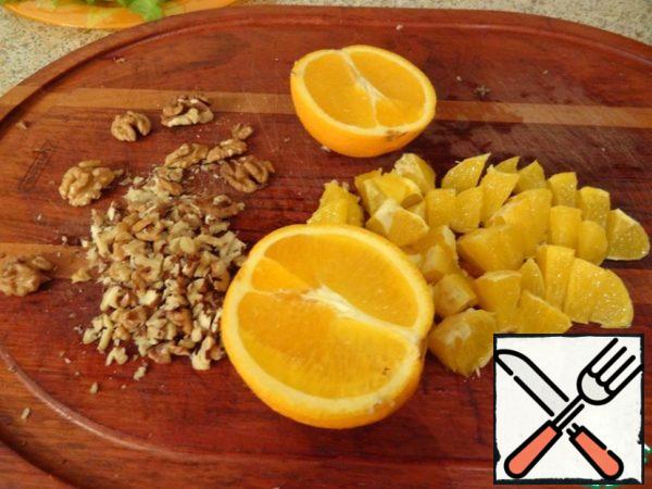 Chop the walnut with a knife, wash the oranges, peel and cut into slices.
