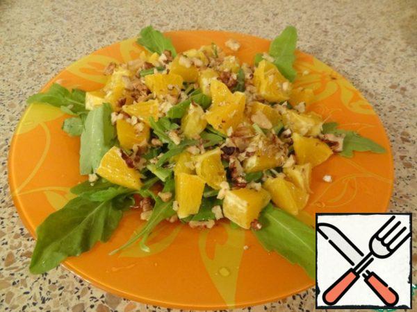 Put the orange and nuts on the arugula.
