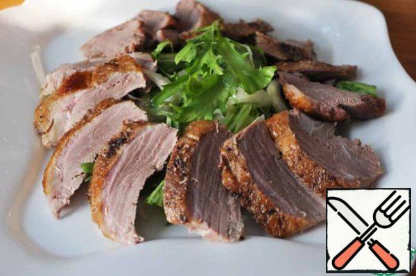Spread sliced duck breast on top of lettuce leaves in a circle.
