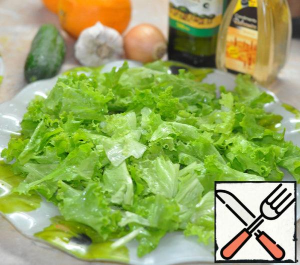 Tear the lettuce leaves into pieces with your hands and put them on a plate.
