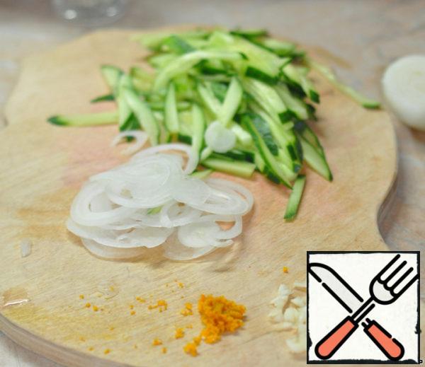 Cut the onion into thin rings.
Chop the garlic.
Grate the zest from the orange on a grater.
Cut the cucumber into thin strips.
