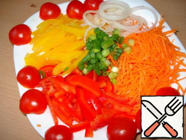 Pepper and carrot cut into strips. Cut the cherry tomatoes in half. Onion rings and some green onion feathers.
