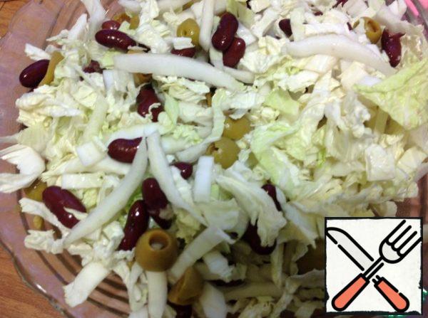 Cut the cabbage and add it to the olives and beans, mix.
