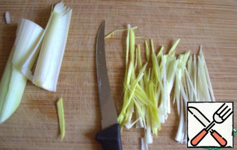 Another part of the leek cut, cut in half and cut with a knife with cutting into very thin strips - this will be the future decoration for the salad.