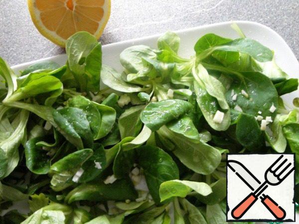 While we have the oven running...
Put the salad on a plate, sprinkle with lemon juice. Chop the garlic and mix with olive oil. Season with salt and pepper. Mix with salad.
If the grapes are large, you need to cut them into halves.
