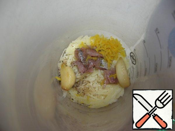 In the blender bowl, add: garlic, pulled from the oil, grated parmesan, a couple of anchovies, zest and lemon juice, freshly ground black pepper and salt. We punch it by adding a little of our fragrant oil there. But not the whole part of the reserve.
