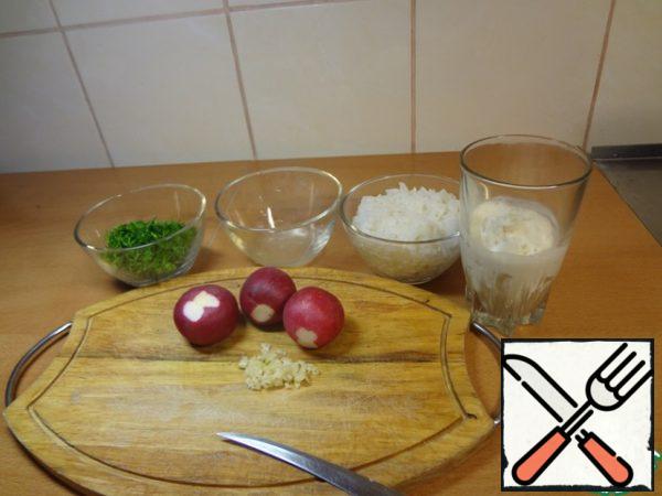 While the rice is cooking, chop the dill greens, chop the radish, leaving 1 piece for decoration, finely chop the garlic clove, squeeze out the lemon juice.
