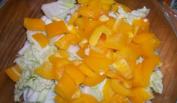 Chop 3-4 leaves of Peking cabbage and bell pepper, peeled from seeds, coarsely and put them on the bottom of a bowl.
