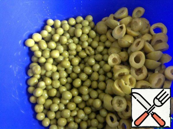 Drain excess liquid from peas, cut olives into rings.