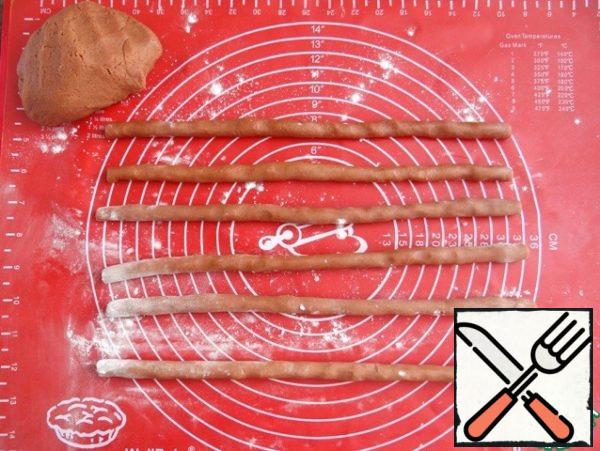 I take the chocolate dough out of the fridge. Sprinkle the table with flour, divide the dough into equal parts - 25-30 g. Roll out the flagella from the dough with a length equal to the length of the mold.
