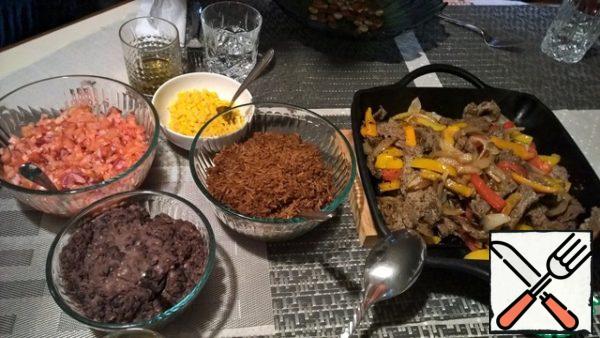 Serve the fajitas in a cast-iron skillet. Next, the side dish is served in separate plates.
