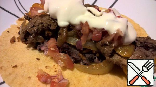 Heat the tortilla corn tortillas in the microwave and serve with fajitas. Every man collects a cake for himself. On the cakes (in the center and along), put the black bean paste, grated cheese, meat with vegetables on top of it, Pico de Gaglia sauce on top and add sour cream to all this. Fold the pie in half, put it on a plate and start eating. Eat these cakes with your hands.