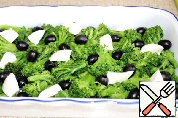 Place large pieces of mozzarella on the broccoli and olives.

