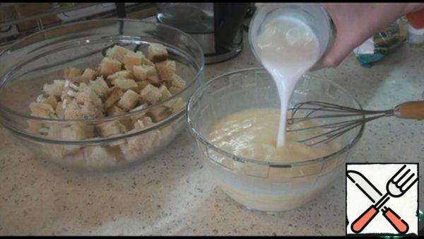 Take the cakes and cut into small cubes. The cylinder has been cut off, we will not use it. In a separate container, beat the eggs, stir with a whisk, add sugar, vanilla sugar, cream and milk. Sugar can be adjusted to your taste depending on the sweetness of the cakes. Stir the whole mixture.
