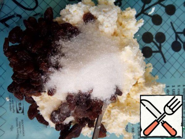 To begin, prepare the filling. Mix cottage cheese with raisins and sugar.
