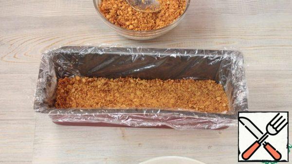 Cover the form with plastic wrap, so it will be easier for you to take the cake out of the mold. Pour a layer of crumbs. It is better not to make a very thick layer of crumbs, so the cake will be soaked better.
