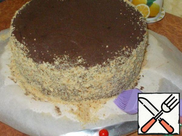 We take the cooled cake out of the refrigerator. Sprinkle the sides with crumbs. Sweep away excess crumbs with a brush.
