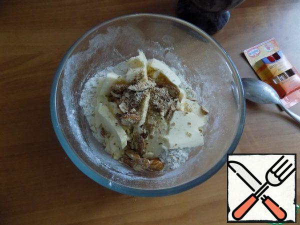 Butter should be taken out of the refrigerator in advance so that it is soft. Cut it into small pieces and spread it with a mixture of nuts and two drops of almond flavor.
