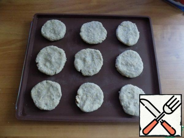 Prepare a baking sheet lined with baking paper. I use a silicone mat. Pieces are torn off from the dough, rolled into small balls, flattening them in the form of cookies. The cookies turned out to be 9 pieces with a diameter of ~ 5 cm and a height of 1 cm. They are placed on a mat at some distance from each other. Preheat the oven to t-180 C.

