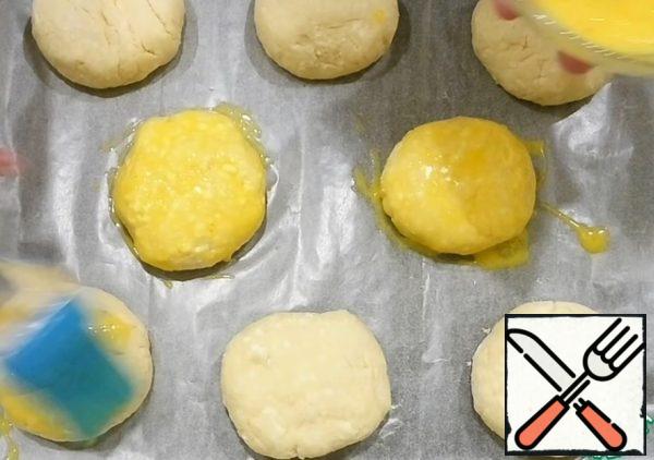 Cover the baking sheet with parchment paper and lay out the buns. With a fork, whisk the yolk, a pinch of salt and milk. Brush each bun with a silicone brush.
