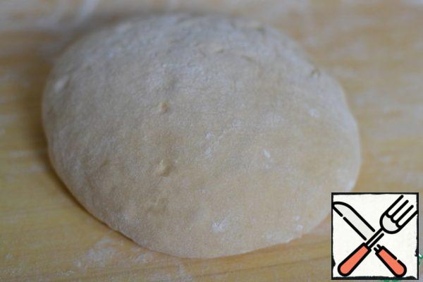 Sprinkle the cutting board with flour.
Lay out the dough and, working with a spatula, roll it in flour. Then press it lightly with your hands.
