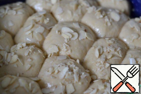 The baking dish (I have a deep round shape) should be greased with sunflower oil.
Place the formed buns in a mold, cover with a towel and leave to come up for 15 minutes.
Brush the buns that have come up with beaten egg whites and sprinkle with almond petals.