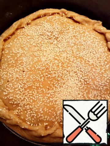 Next, cover the cake with dough, grease with egg and sprinkle with sesame seeds. Put it in the oven. Bake the cake at 180 degrees for 40-45 minutes.