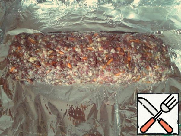 Cover the baking sheet with foil or parchment paper in several layers. It is advisable to form the sides so that the juice does not spread.
We spread the minced meat, carefully form a low bar with our hands.

