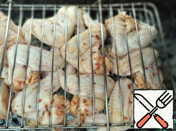 Then put the chicken wings on the grill and cook until browned on the coals.
