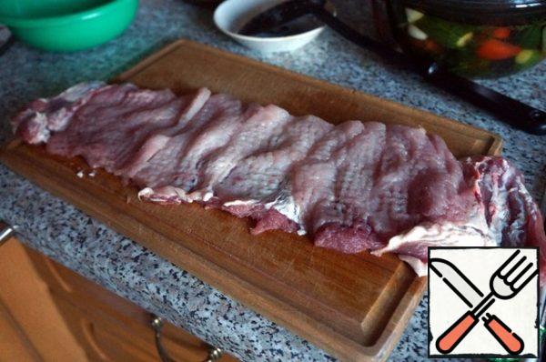 A piece of pork is not cut along to the end, we continue to make the same incisions so that at the end the meat can be unwrapped with a ribbon.
Cover with cling film and beat off with a hammer on both sides.

