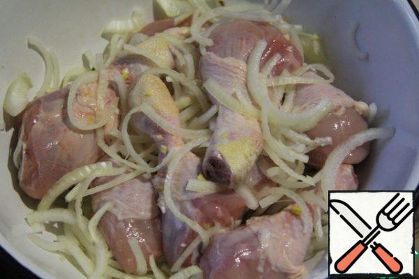 Cut the chicken into portions. Cut the onion into half rings and mix with the chicken.
