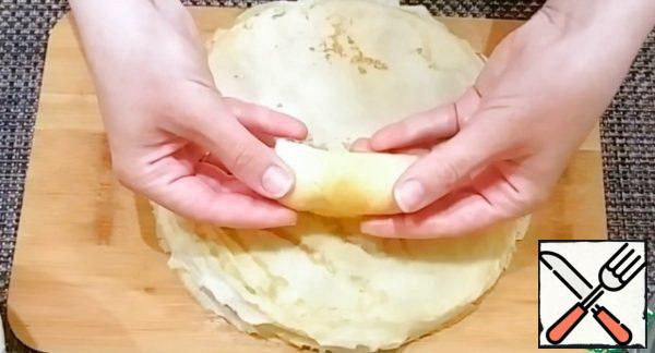 Cut the pancakes in half. Place the cottage cheese on the center of the wide edge, cover the side edges with it and wrap the pancake. Repeat the same with all the pancakes.
