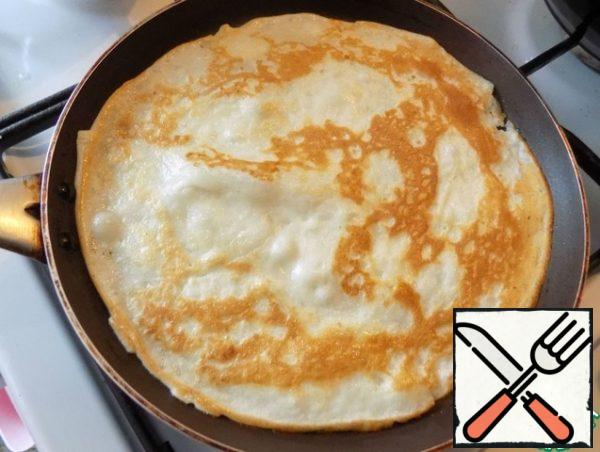 Bake pancakes. Heat the pan well. My frying pan is D-24 cm. To bake the first thin pancakes, the mold can be oiled. Pour the dough into a thin layer, spreading it over the entire plane of the mold, tilting the mold from side to side. When the pancake on one side acquires a beautiful color and grabs, easily turn it over. From this amount of dough I got 9 pieces of thin pancakes D-24 cm.
