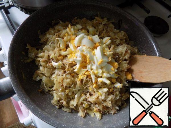 Prepare the filling. Pour oil into a frying pan, heat it up and put the garlic cloves. Fry them for a minute so that the garlic gives its flavor to the oil, and take it out. In the fragrant oil, put the onion, cut at random. We brown it and add chopped cabbage to it. Fry the cabbage until tender, not very much. It will take about 15 minutes. At the end, add salt and pepper to taste with freshly ground black pepper if desired. Add sour cream, stir, reduce the heat to a minimum, cover with a lid and simmer the cabbage for 3-5 minutes. At the end, add chopped hard-boiled eggs to the filling. The filling is ready.
