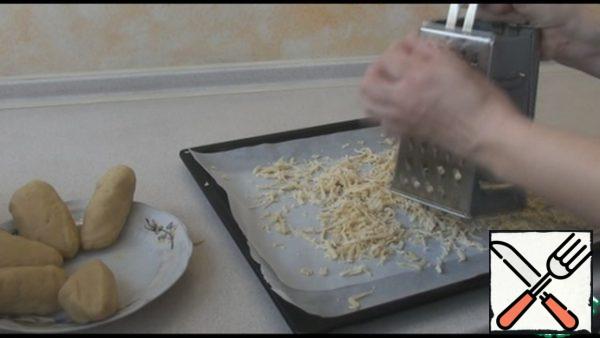 We rub the frozen dough on a coarse grater, evenly distributing it on a baking sheet. Cover the baking sheet with parchment paper. Bake in a preheated 180 degree oven for 20 minutes. Remove the finished pie from the oven and let cool for about 20 minutes.
