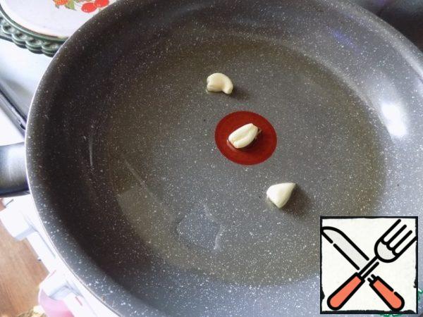 Pour olive oil into a saucepan or a high frying pan. You can also take sunflower oil. Heat the oil and spread the peeled and crushed garlic cloves with the flat side of the knife. Hold them in the oil for a minute so that they give their flavor to the oil, and take them out.
