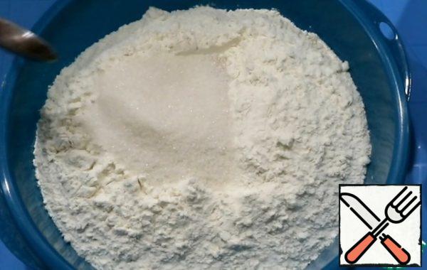 Add yeast, salt and sugar to the sifted flour. Stir with a spoon.
