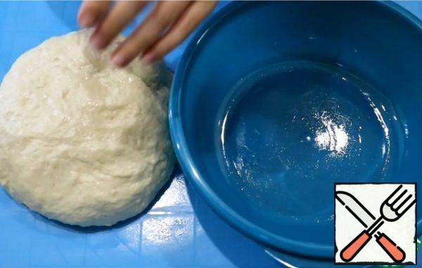 Sprinkle the table with flour and knead the dough for about 5 minutes. Grease a bowl with vegetable oil, lay out the dough, cover with a towel and send it to a warm place for 40 minutes.

