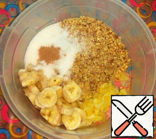Prepare the stuffing.
Nuts chop into crumbs.
Bananas cut into circles.
Peel the lemon and cut into small pieces.
In a bowl combine nut crumbs, lemon, banana and sugar with cinnamon.
Mix the filling, slightly crushing bananas with a spoon.
