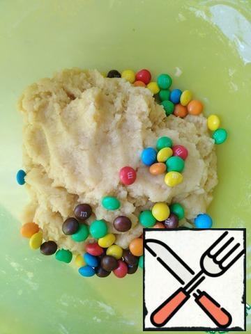 Knead the dough and add a homogeneous candy M&m's, mix.
