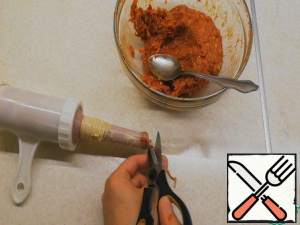 By rotating the piston handle, move the filling to the edge of the nozzle so that there is no air inside the shell initially. Pull out a part of the shell sufficient to tie a knot, tie a knot, cut off an extra tail with scissors.
