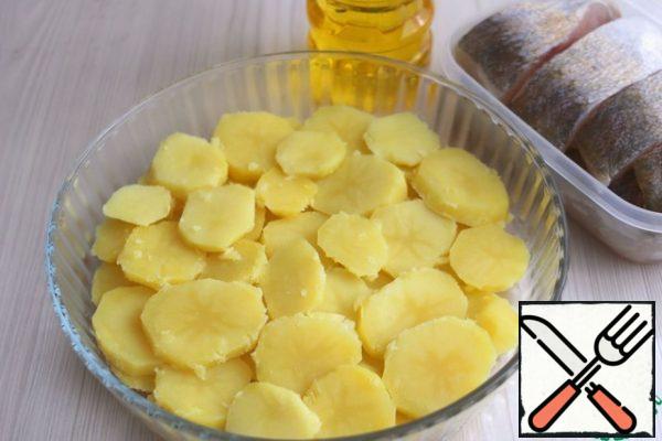 Boil potatoes (7 pcs.) until Al dente in salted water, cool. Cut into plates 0.5 - 0.7 mm thick . Pour 2 tablespoons of vegetable oil on the bottom of the baking dish, lay out the potatoes with plastic.
