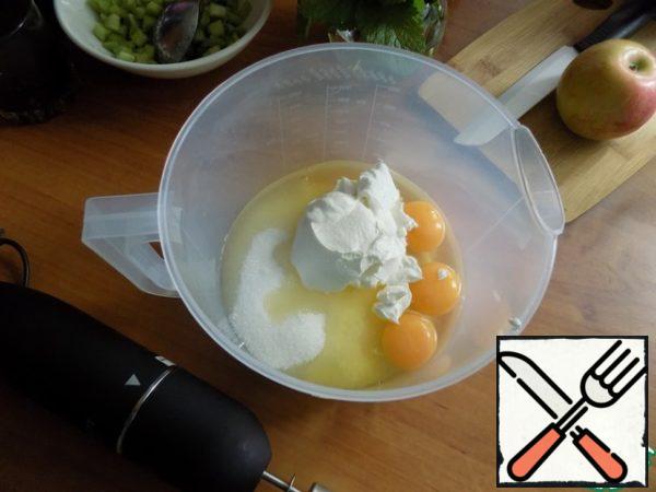 Make the dough. In a bowl put sugar, eggs and sour cream. With a whisk combine. I'll use an electric whisk.
