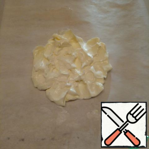 Now let's do the butter. On a sheet of parchment in the center of the hands flatten a piece of soft (not melting!) butter (125 g).