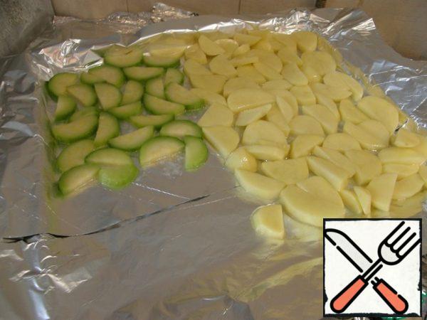 Zucchini spread on a baking sheet with potatoes.