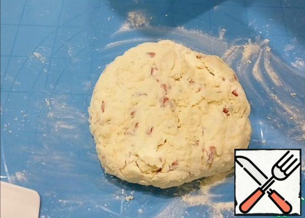 Add kefir, mix with a spoon, and then with your hands. Sprinkle the table with flour and knead the dough a little, it will turn out a little sticky.